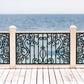 Black powder coated laser cut metal outdoor deck railing panel featuring traditional wrought iron scrollwork installed on seaside wooden patio