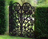Black powder coated laser cut metal double driveway gate featuring ornate scrollwork pattern with circular floral medallions installed in garden setting