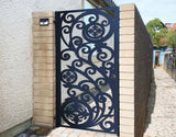 Black powder coated laser cut metal pedestrian garden gate featuring ornate scrollwork and circular medallion pattern installed between brick walls