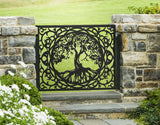 Black powder coated laser cut metal pedestrian garden gate featuring central circular tree of life pattern installed between natural stone pillars