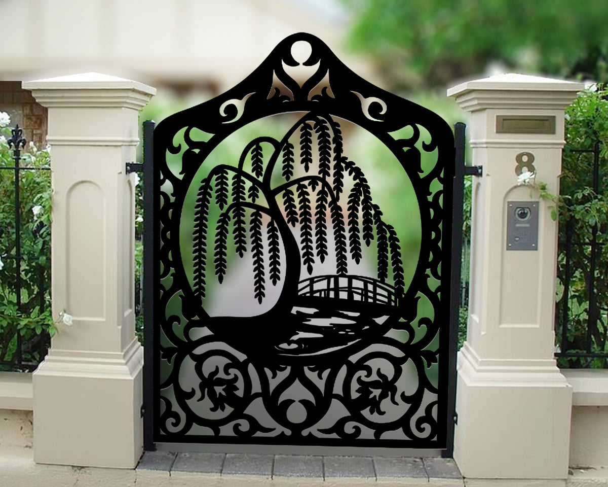 Black powder coated laser cut metal pedestrian garden gate featuring arched crest top with willow tree and bridge scene installed between beige concrete pillars