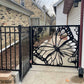 Black powder coated laser cut metal side pedestrian gate featuring large monarch butterfly wing and flower pattern installed next to residential fence