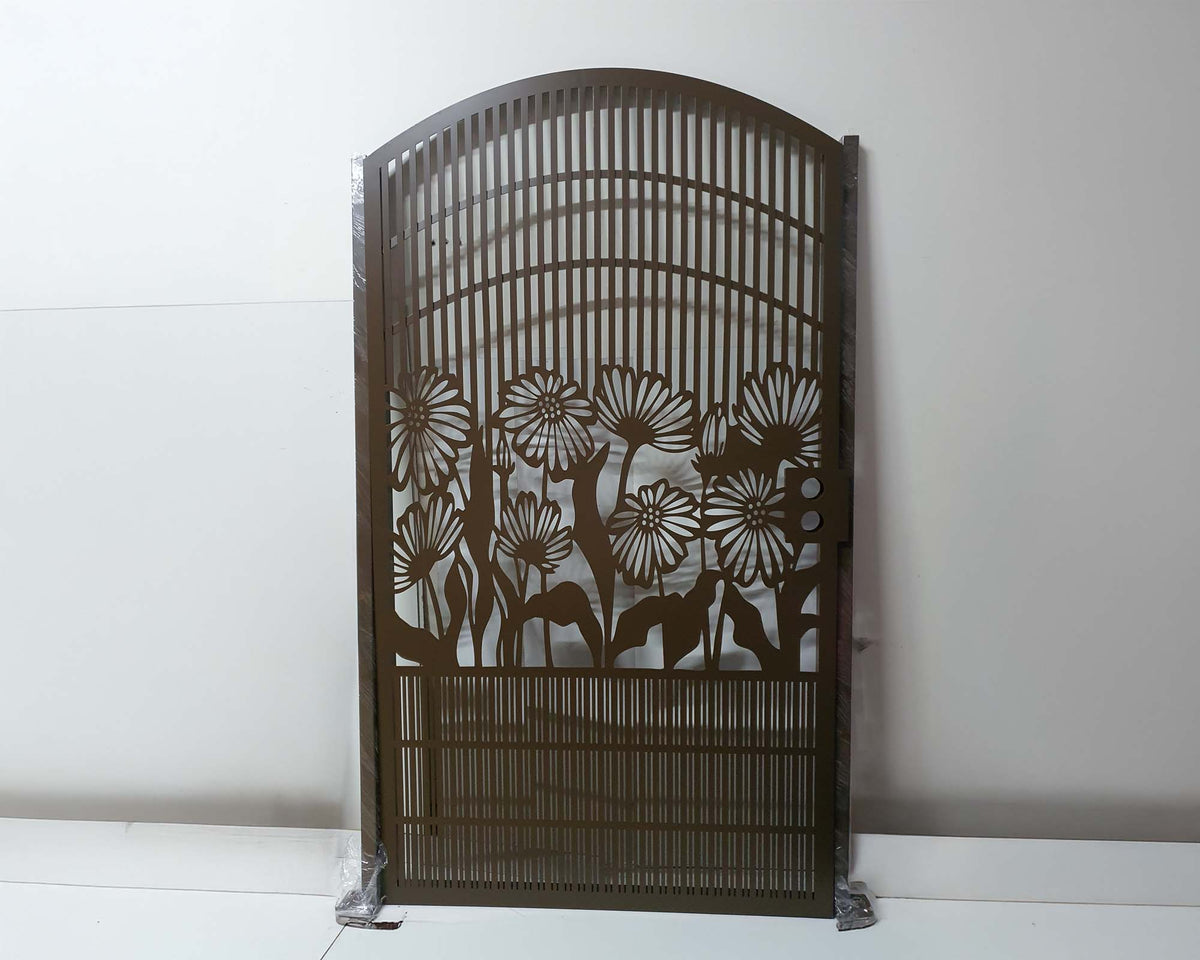 Brown powder coated laser cut metal pedestrian garden gate with arched top frame featuring central daisy flower garden pattern and vertical slatted bars