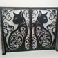 Matte black powder coated laser cut metal double garden gate featuring ornate cat silhouette pattern installed between brick pillars