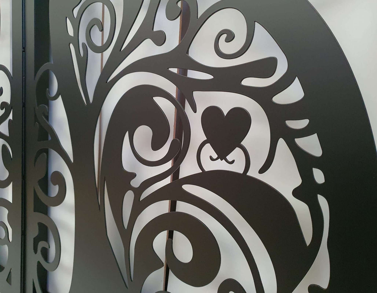 Metal garden gate featuring ornate cat silhouette pattern installed between brick pillars
