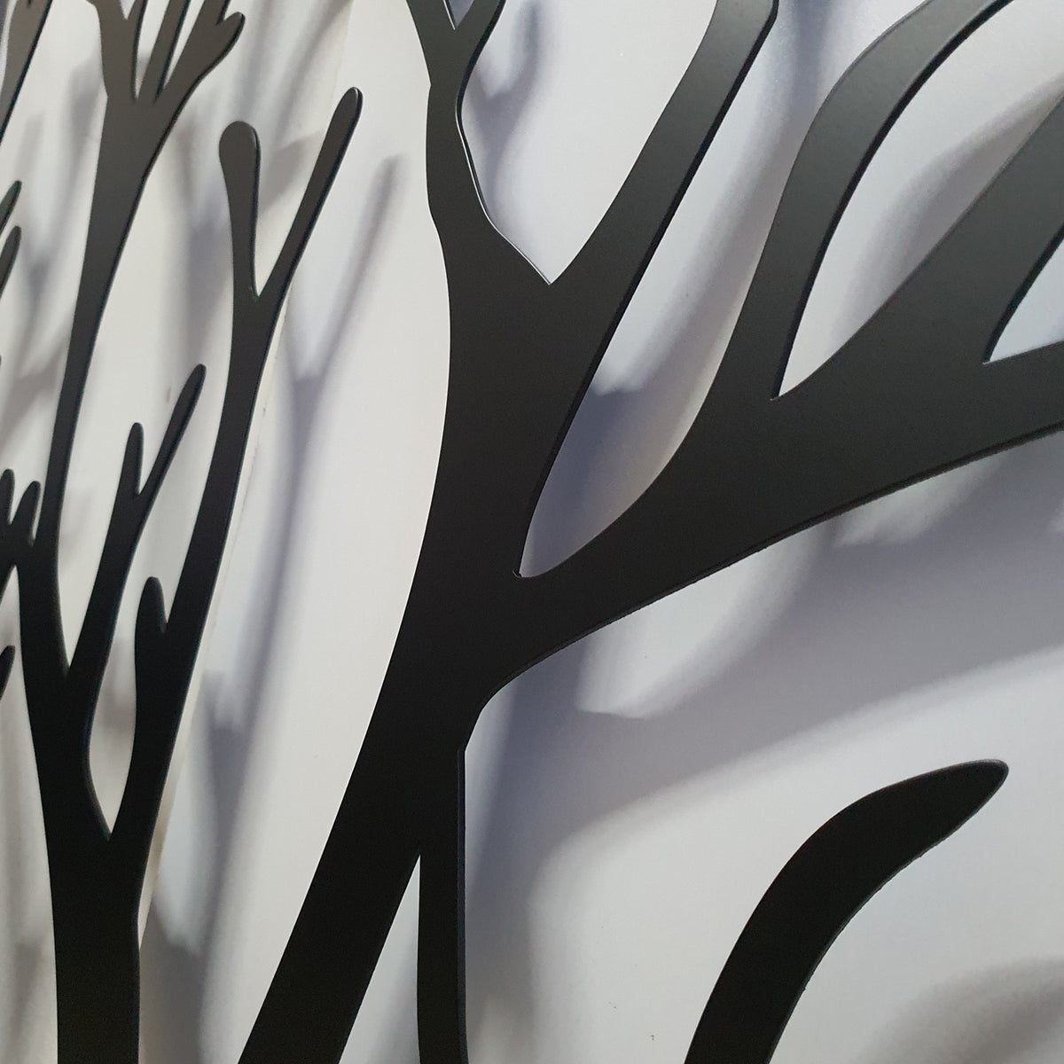 Perspective close-up detail of matte black powder coated laser cut metal gate featuring organic tree branch pattern
