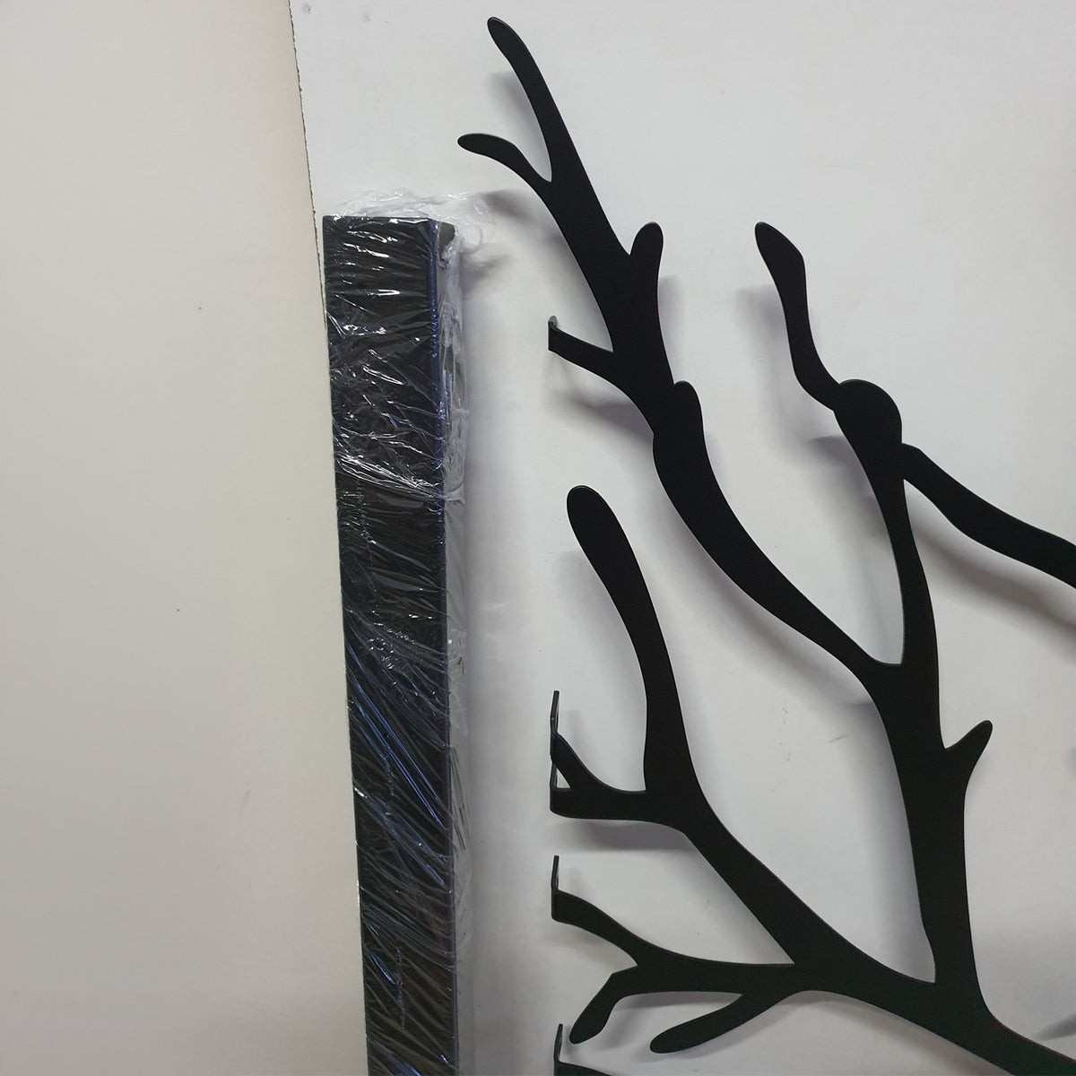 Close-up detail of black powder coated laser cut metal gate showing side mounting post frame and organic tree branch pattern