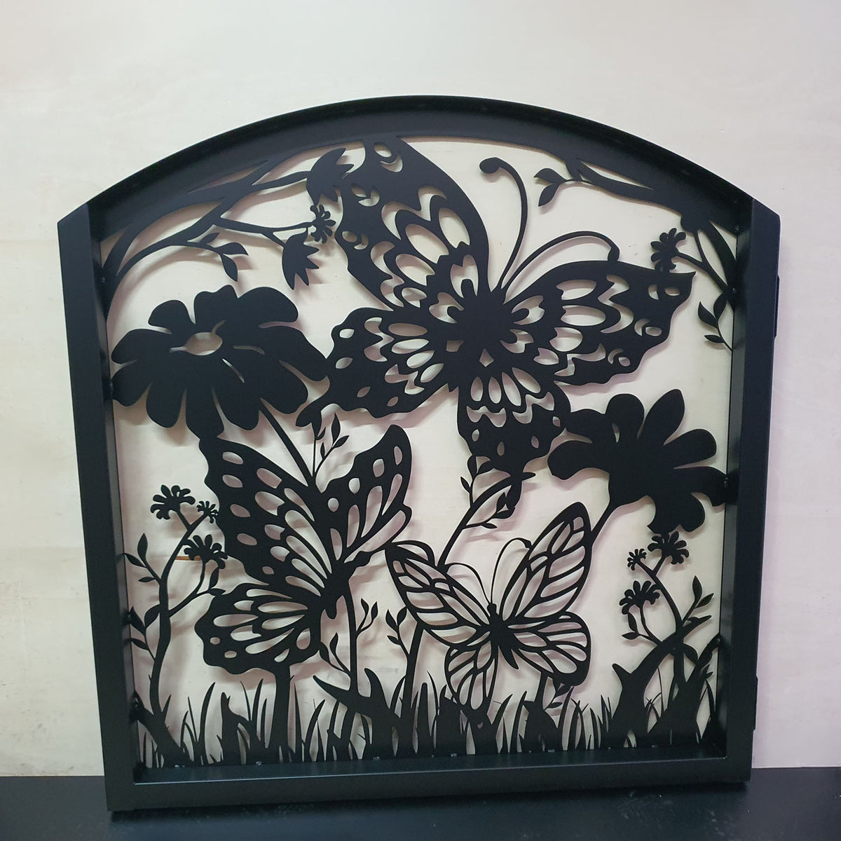 Matte black metal laser cut pedestrian garden gate featuring curved arched top frame with butterflies and botanical wildflower pattern