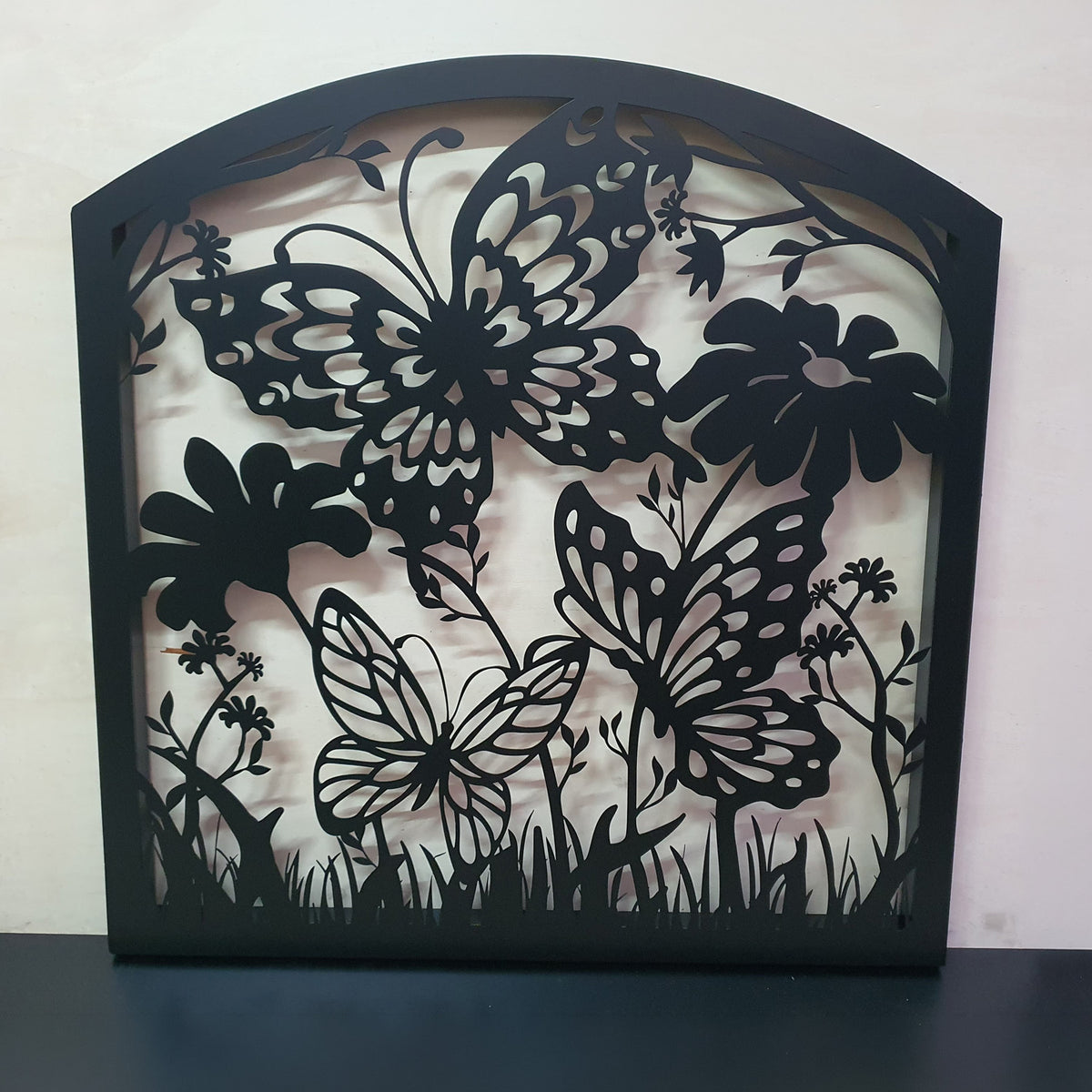 Black metal laser cut pedestrian garden gate featuring curved arched top frame with butterflies and botanical wildflower pattern