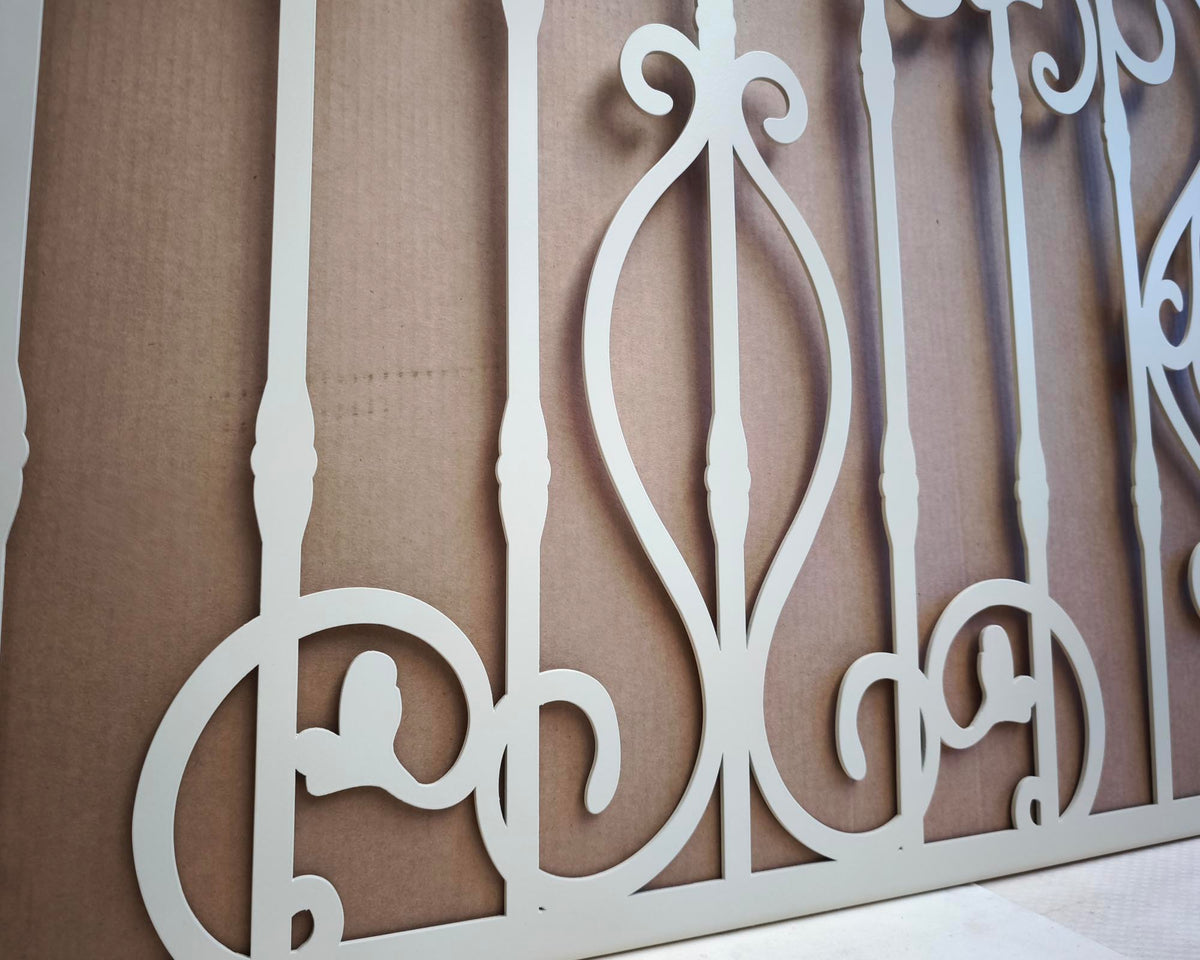 White powder coated laser cut metal outdoor deck railing panel featuring traditional wrought iron scrollwork installed on seaside wooden patio