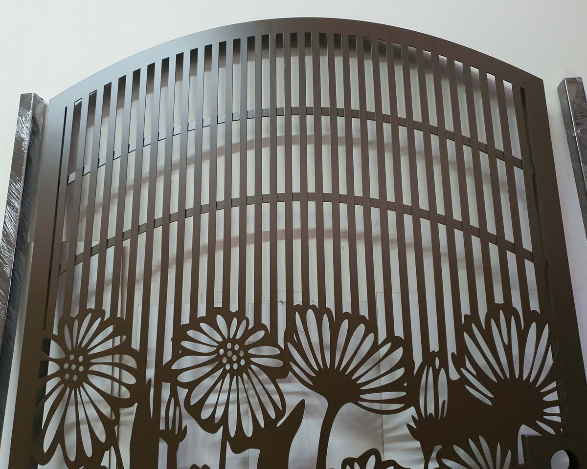 Matte brown powder coated laser cut metal pedestrian garden gate with arched top frame featuring central daisy flower garden pattern and vertical slatted bars