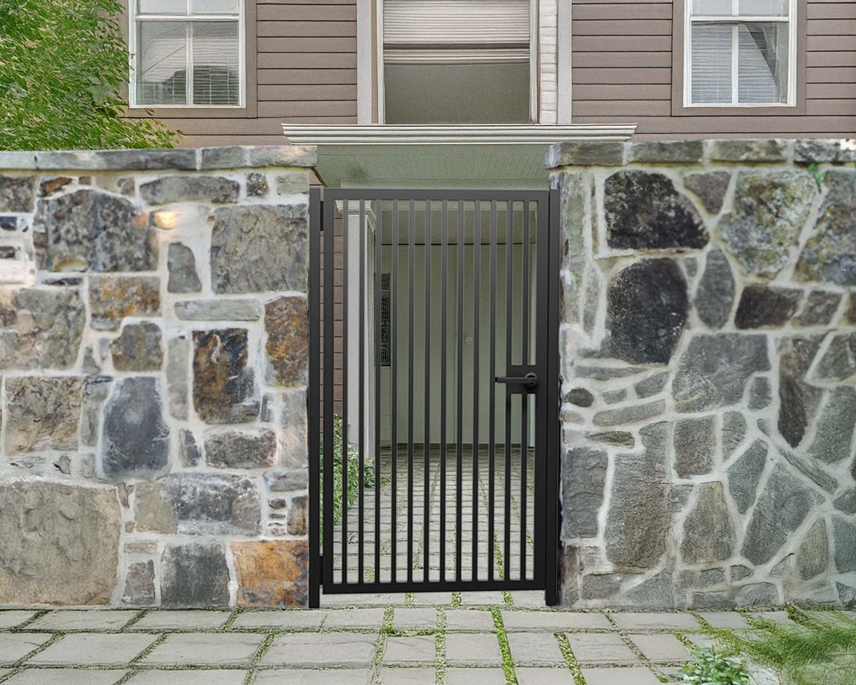 Black powder coated modern metal pedestrian garden gate with vertical slatted pattern installed between natural stone walls