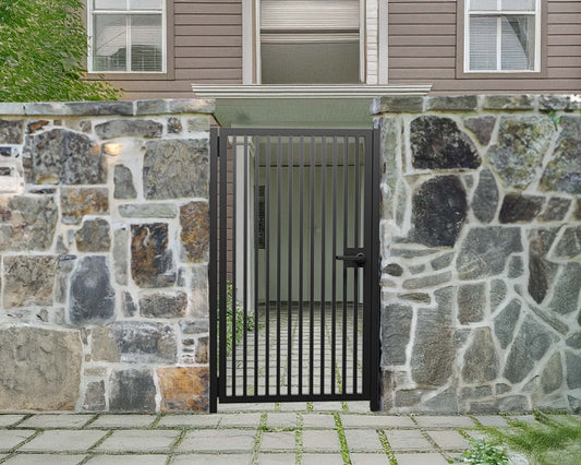 Black powder coated modern metal pedestrian garden gate with vertical slatted pattern installed between natural stone walls