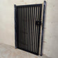 Matte black powder coated modern metal pedestrian garden gate featuring vertical slatted bar pattern and side mounting posts