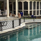 Two English bulldogs kept safely away from the pool by a no drill freestanding metal dog pool fence installed on curved stone coping