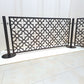 Expandable no drill pool fence with connected laser cut panels in dark bronze powder coat, freestanding on round base stainless steel posts