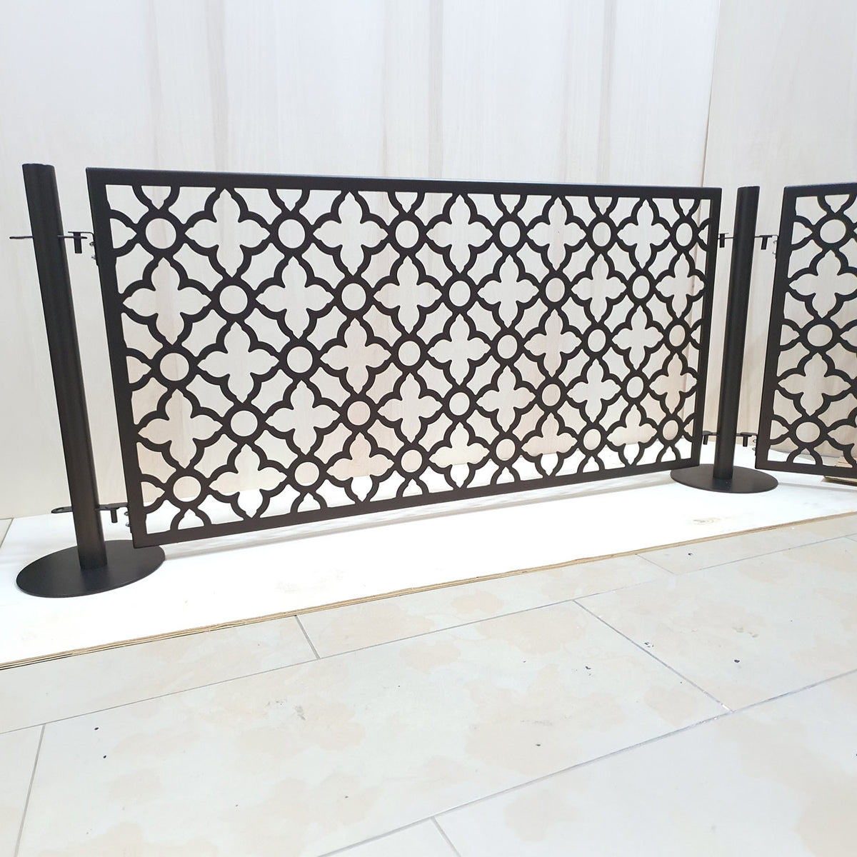 Expandable no drill pool fence with connected laser cut panels in dark bronze powder coat, freestanding on round base stainless steel posts