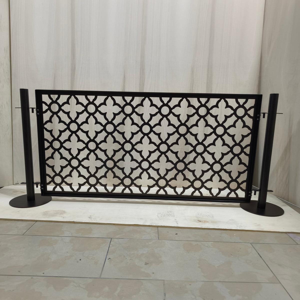 Back view of a laser cut dog pool fence panel showing the welded frame and pin brackets that mount onto two freestanding round base posts