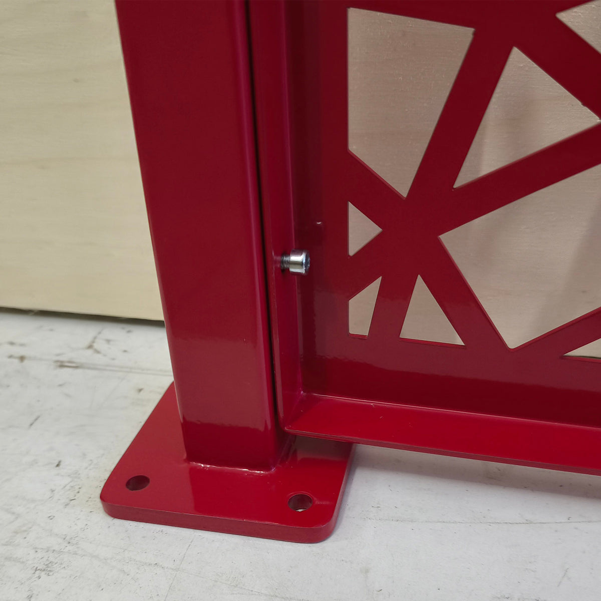 Surface mount base plate of a steel post holding a red honeycomb Voronoi laser cut metal fence panel