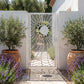 Laser cut metal garden gate with a sun and moon eclipse pattern, powder-coated in matte white, set between white stucco walls with potted olive trees and lavender.