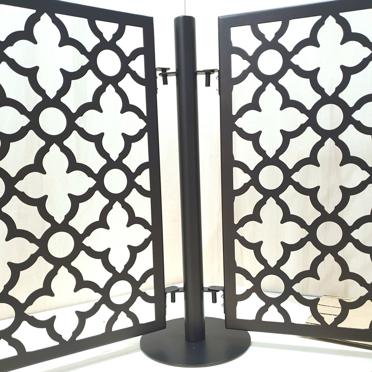 Close up front view of two laser cut quatrefoil pattern pool fence panels connected to one round base post with upper and lower drop in pins