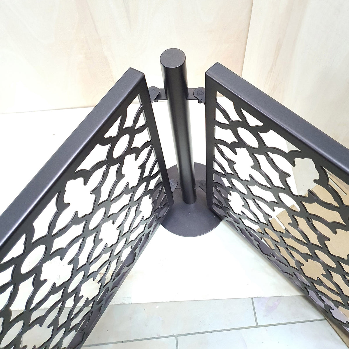 Top view of a dog pool fence corner where two laser cut panels pivot on drop in brackets around one freestanding stainless steel post