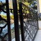 Close up of the tool free hook bracket connecting a laser cut aluminum dog pool fence panel to a stainless steel post beside the pool