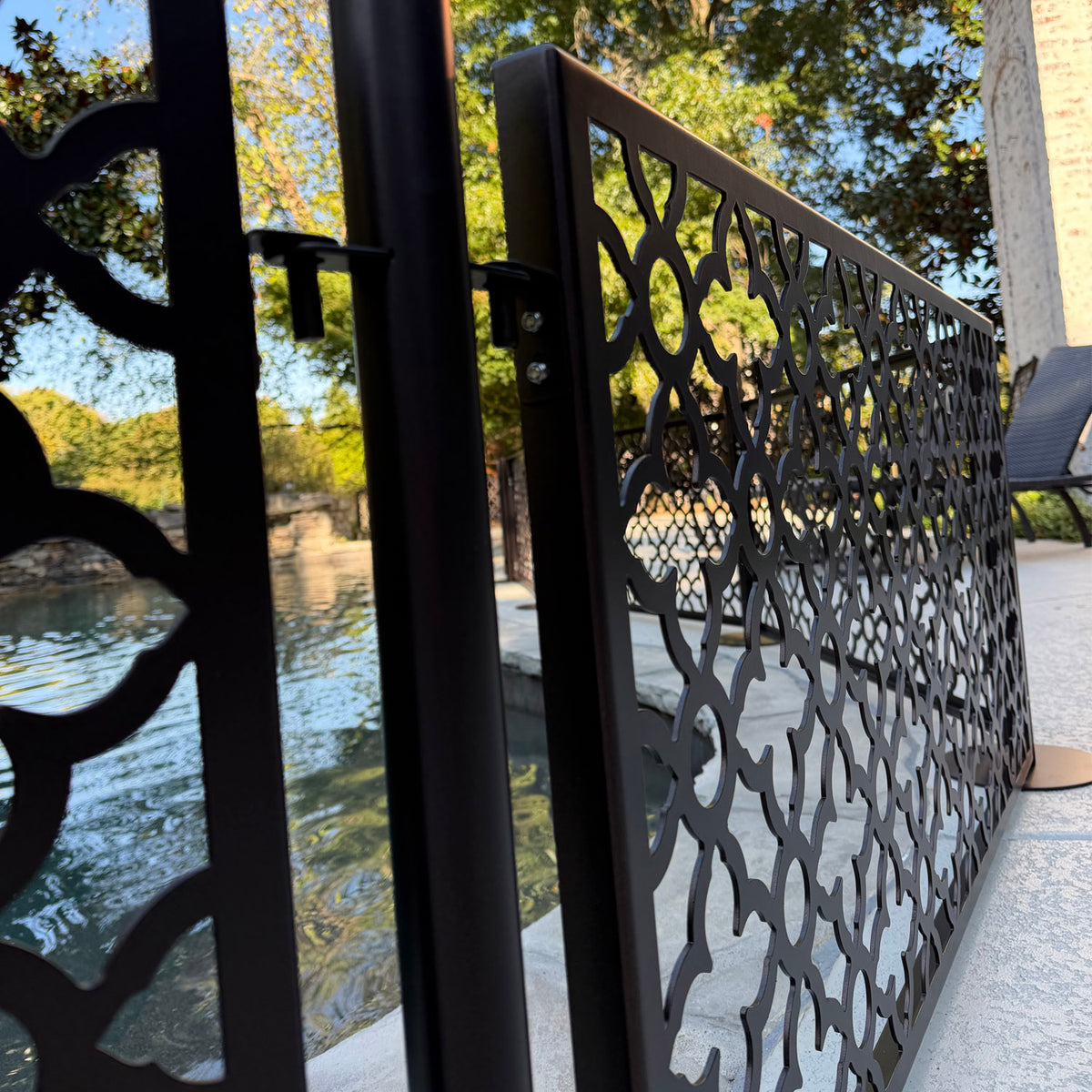 Close up of the tool free hook bracket connecting a laser cut aluminum dog pool fence panel to a stainless steel post beside the pool