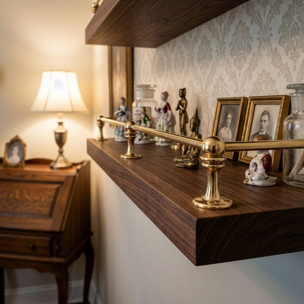 Close-up view of polished unlacquered solid brass gallery rail mounted on a dark wood shelf holding vintage collectibles and picture frames.